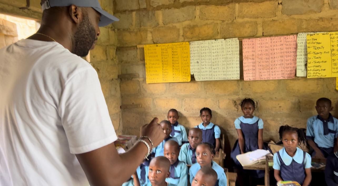 Dr. Michael Ajilo interacting with pupils in a classroom.